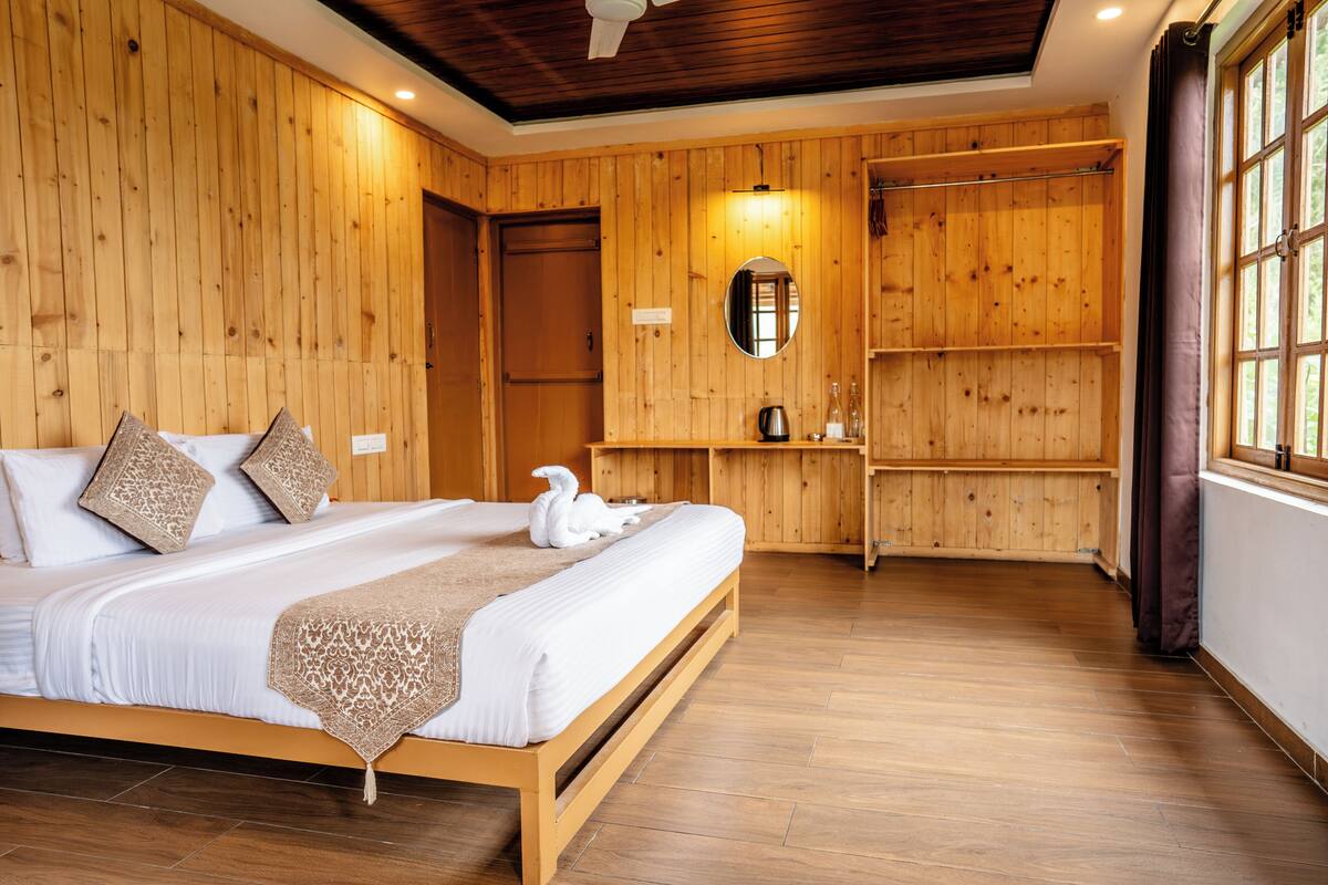 Ein Zimmer mit Holzwänden, einem Bett, einem Spiegel und einem Regal mit einem Wasserkocher.