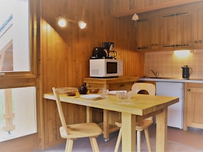 A wooden interior with a kitchen area, including a microwave, a kettle, and a dining table with chairs. - Studio in Méribel - Near slopes, Parking, Pets allowed (Méribel)