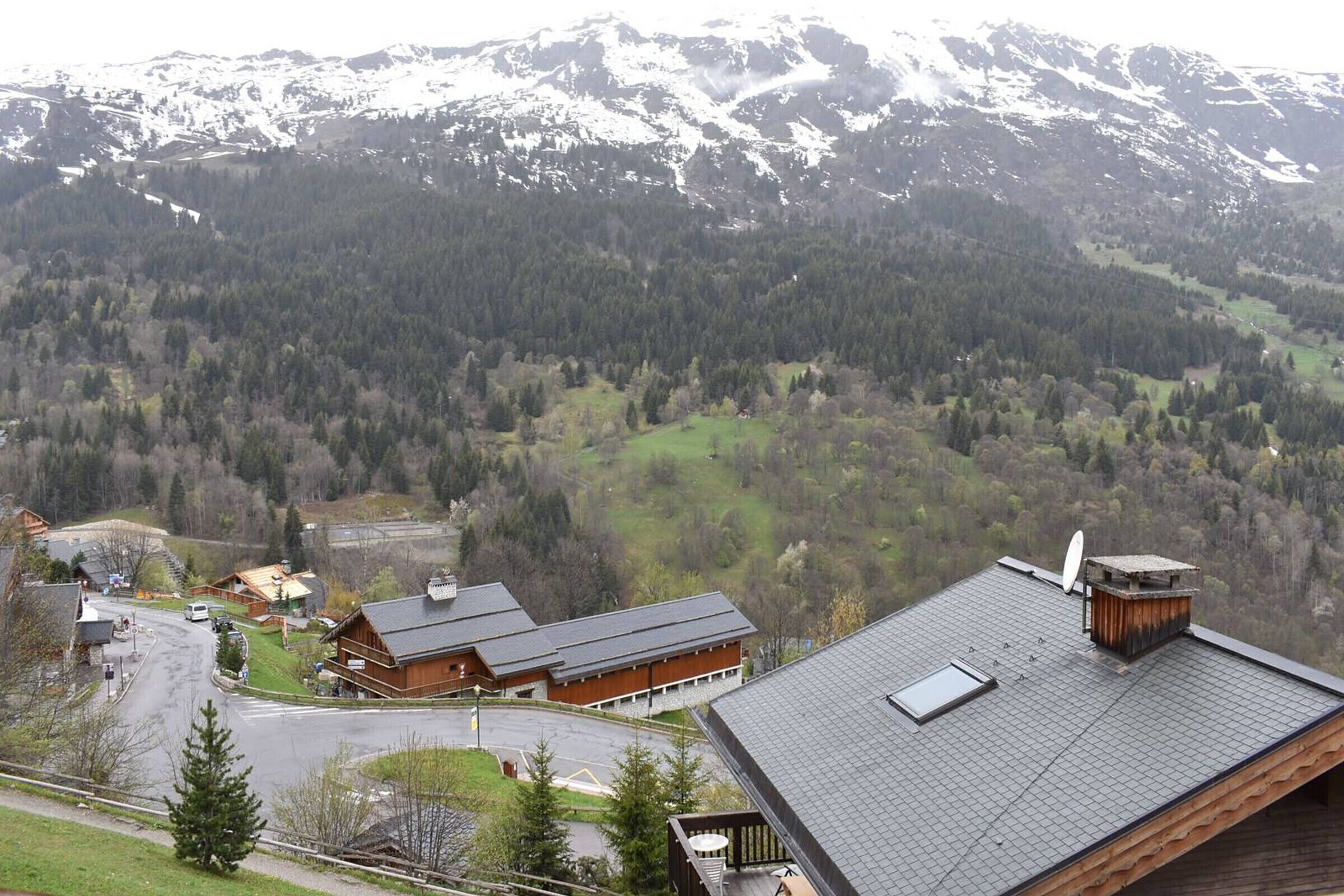 Eine Lodge mit geneigtem Dach, einer Satellitenschüssel und Blick auf ein bewaldetes Tal mit Bergen im Hintergrund.