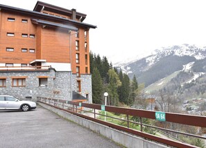 Un bâtiment moderne avec une façade en pierre et des étages supérieurs en bois, offrant une vue sur un paysage montagneux.