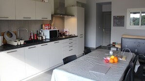 Ett modernt kök med vita skåp, en mikrovågsugn och ett matbord som är dukat med frukt.
