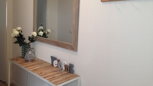Un pasillo con un espejo, una consola de madera con objetos decorativos y un perchero de pared.
