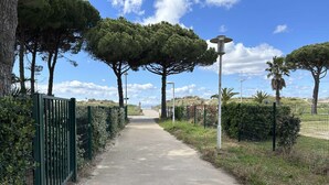 A paved pathway flanked by green fences and trees, leading to a distant view. - Air-Conditioned Studio with Terrace, Pool & Parking - Sleeps 4, Steps from Port Camargue Beach (Port Camargue)