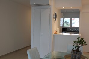 Una cocina moderna con una mesa de vidrio, armarios blancos y vistas al exterior a través de una ventana.