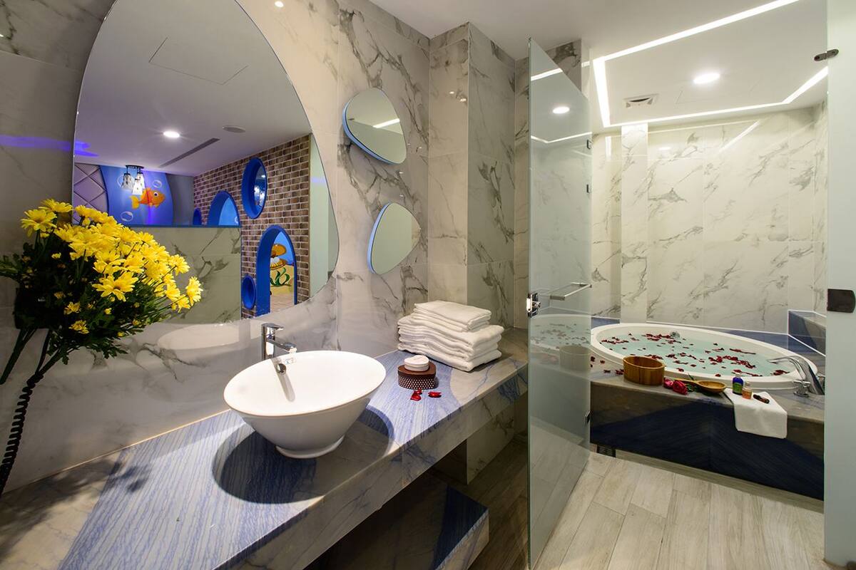Un baño moderno con lavamanos de mármol, un espejo grande y cabina de ducha con paredes de vidrio.