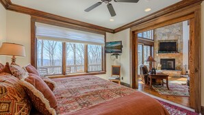 A spacious bedroom with a large bed, a television, and a stone fireplace.