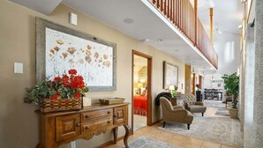 Amplia sala de estar con una consola de madera, un cuadro floral grande y una zona de estar acogedora con un sofá y sillones.