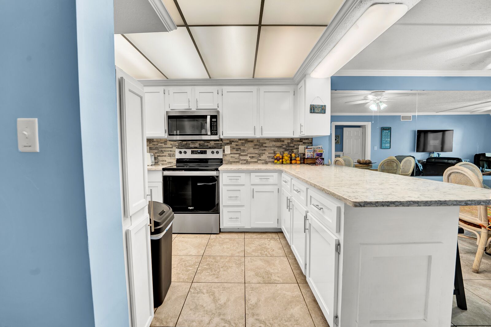 A modern kitchen with white cabinetry, a built-in oven, microwave, and granite countertop.