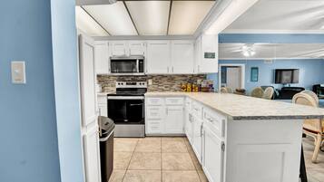 A modern kitchen with white cabinetry, a built-in oven, microwave, and granite countertop.
