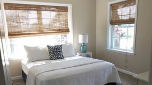 A bedroom with a bed, two windows with blinds, a bedside lamp, and a door. - New Home On Rural Eastern Shore Farm (Cape Charles)