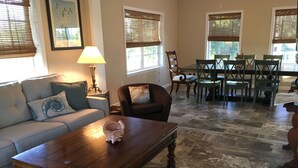 A living room with a wooden coffee table, a sofa, a dining table with chairs, and a lamp. - New Home On Rural Eastern Shore Farm (Cape Charles)