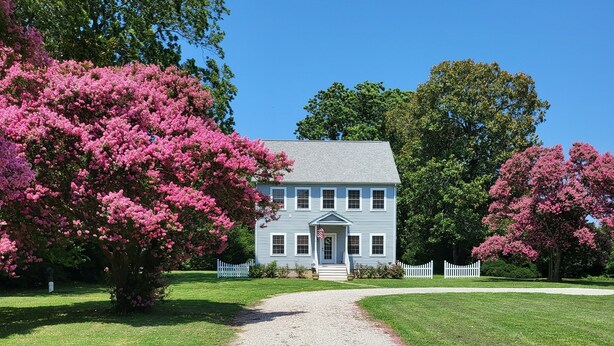 A house with a gravel driveway leading to a white picket fence. - New Home On Rural Eastern Shore Farm (Cape Charles)