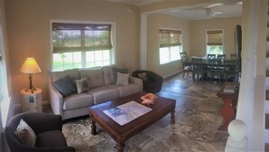 A living room with a sofa, armchair, coffee table, and dining area with chairs and a table. - New Home On Rural Eastern Shore Farm (Cape Charles)