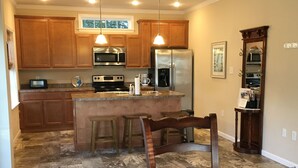 A kitchen with wooden cabinets, stainless steel appliances, and a central island with stools. - New Home On Rural Eastern Shore Farm (Cape Charles)