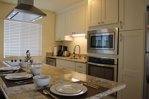 A modern kitchen with white cabinets, stainless steel appliances, and a granite countertop.