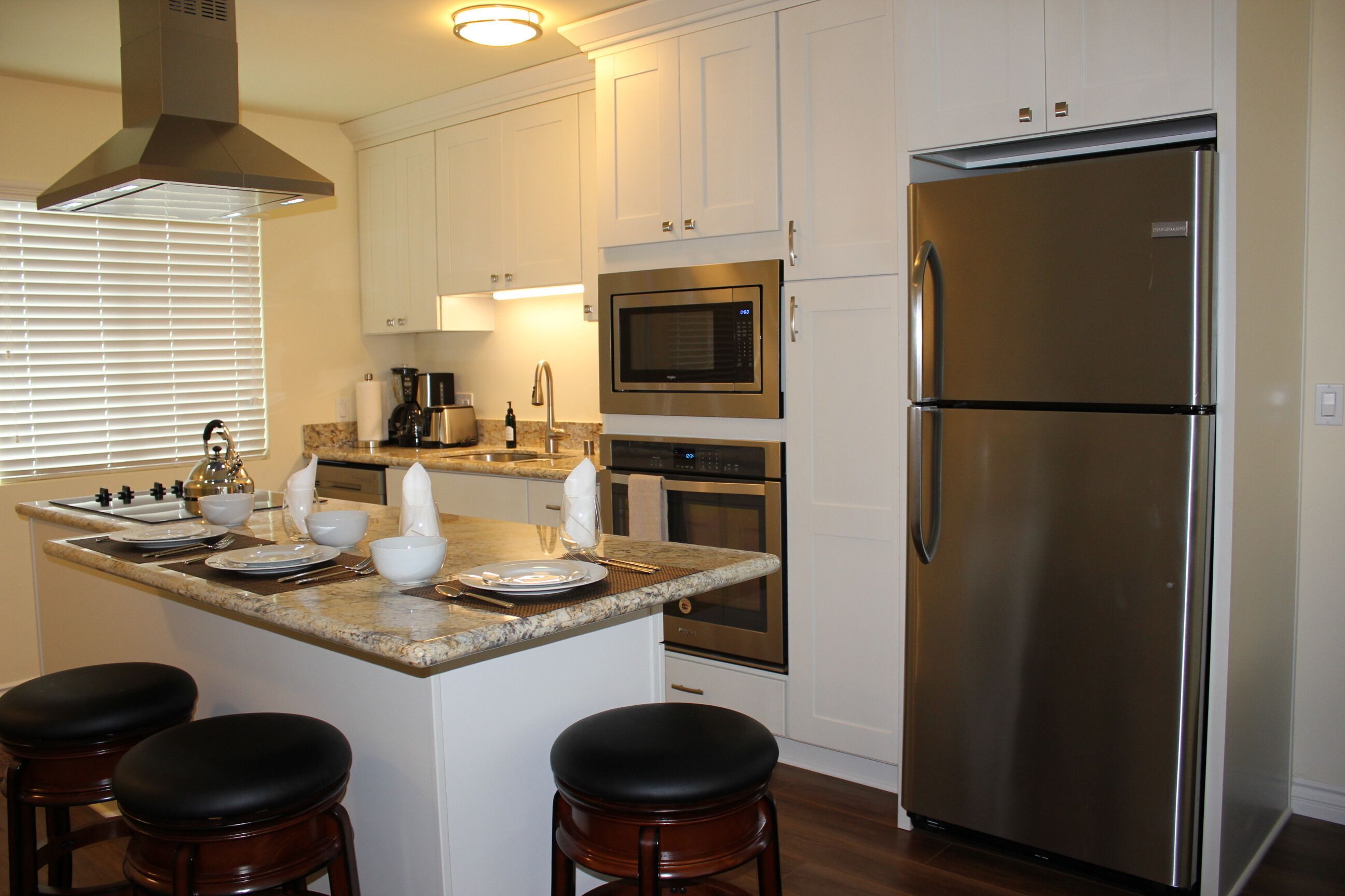 A modern kitchen with a central island, stainless steel appliances, and bar stools.