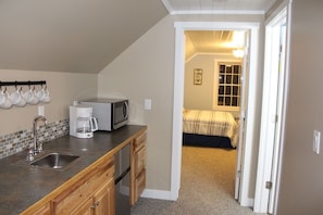Cozy retreat with a kitchenette, bedroom, and window offering a view of the outside.
