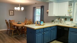Una cucina moderna con mobili blu, un tavolo da pranzo in legno e una lavastoviglie integrata.