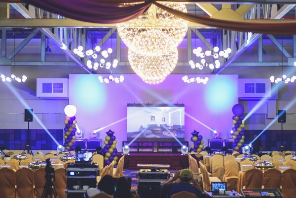 A conference room with a stage, rows of chairs, and a large chandelier. - Aman Hills Hotel (Bandar Seri Begawan)
