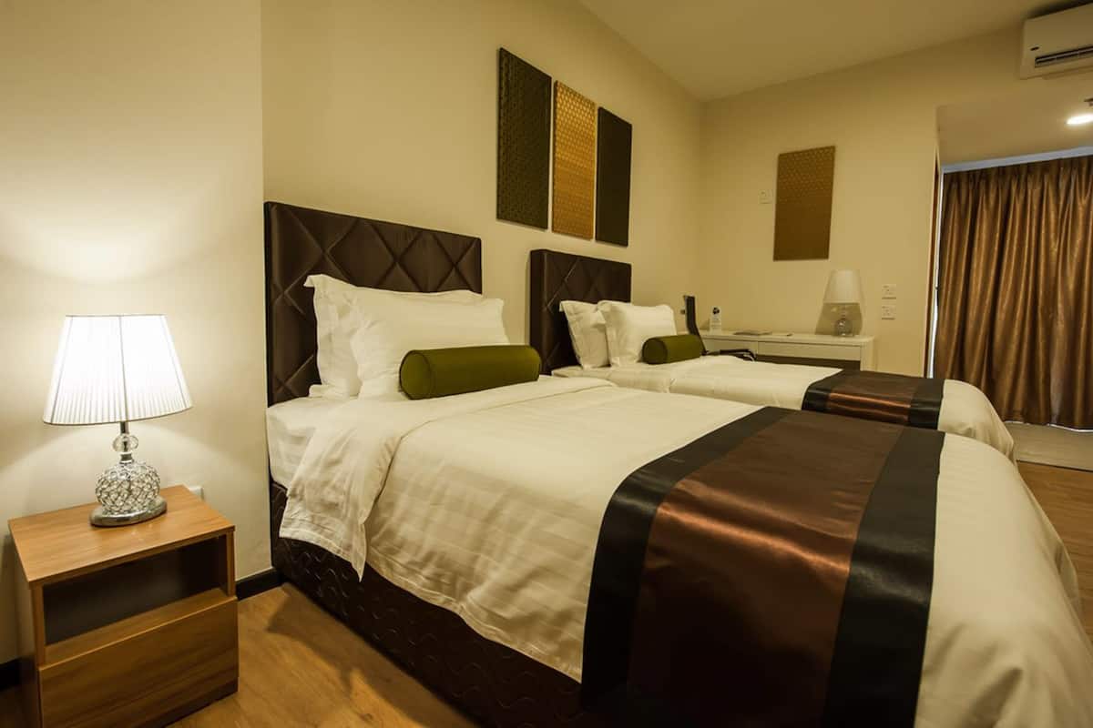 Une chambre d’hôtel avec deux lits, une table de chevet avec une lampe et un miroir.