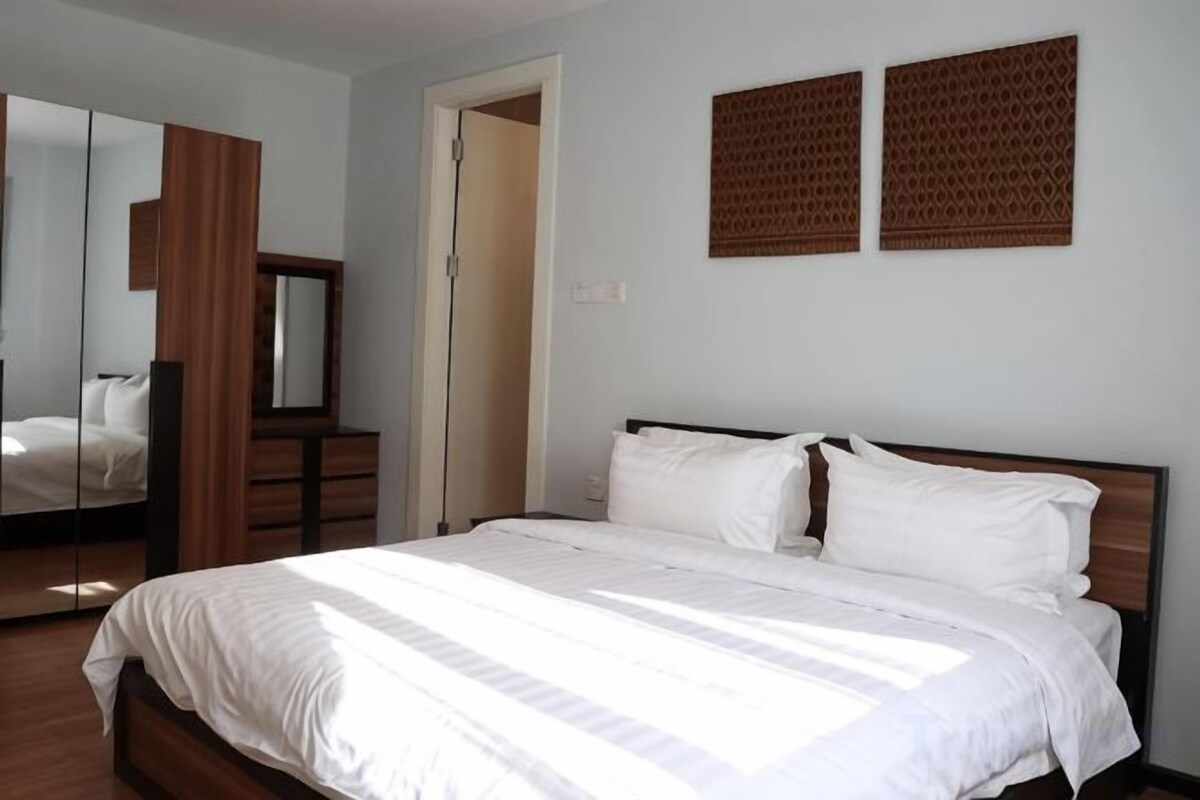 A bedroom with a bed, a dresser, a mirror, and two wall-mounted panels.