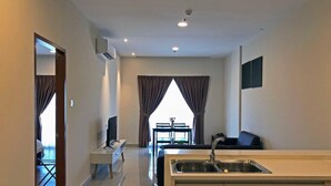 Een moderne hotelkamer met kitchenette, een eethoek en een groot raam met gordijnen.