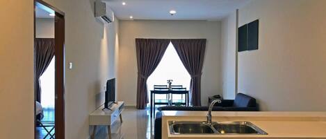 A modern hotel room with a kitchenette, a dining area, and a large window with curtains.