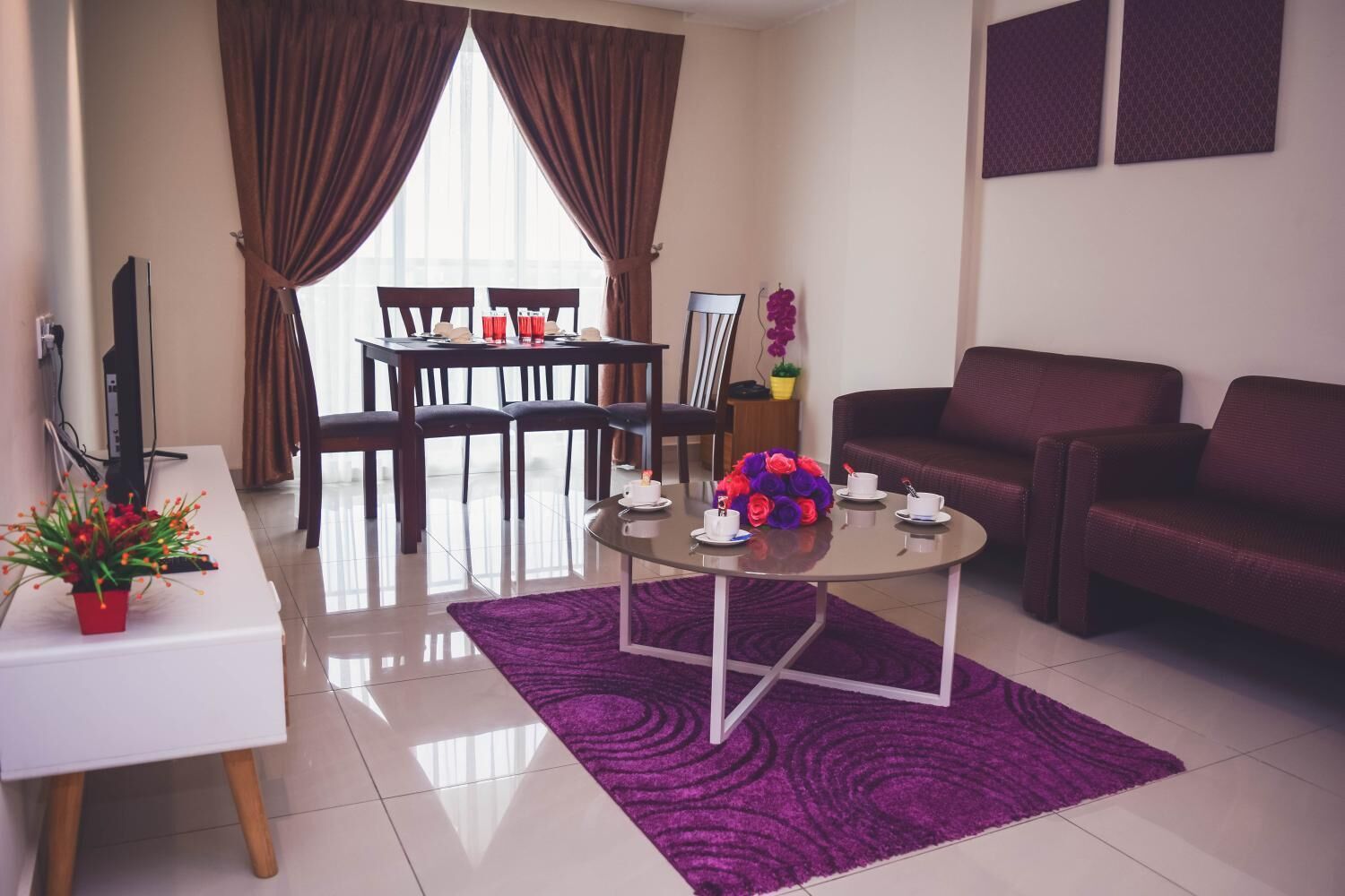 A modern living room with a dining area, a sofa, and a coffee table with flowers.
