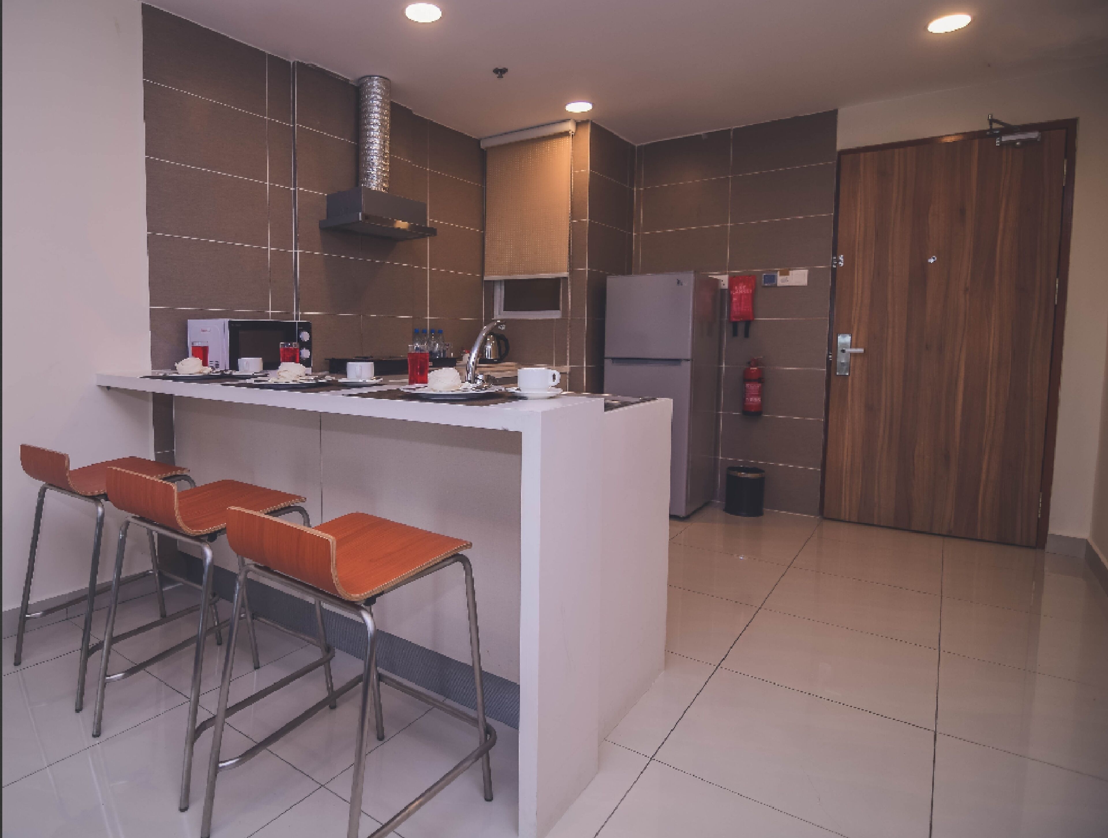 A modern kitchen with a central island, bar stools, a microwave, and a refrigerator.
