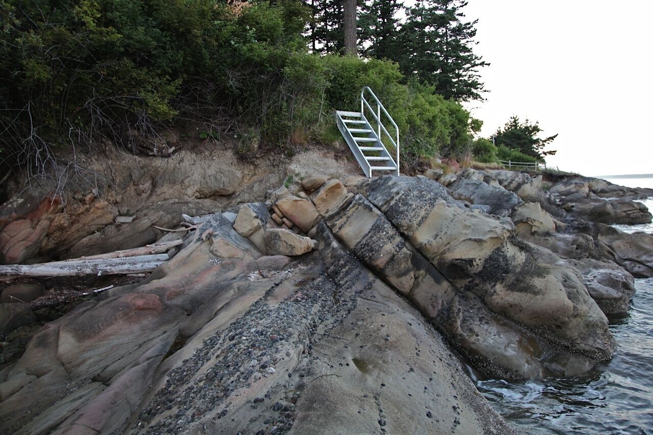 Eine felsige Küstenlinie mit einer Metalltreppe, die zu einer höheren Lage führt.