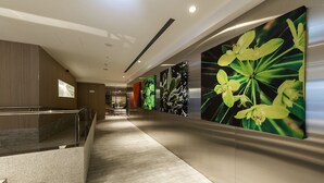A modern hotel corridor with a marble floor, a staircase, and large floral wall art. - Inhouse Hotel Grand (Taichung)