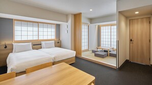 A modern hotel room with a large bed, a wooden table, and a seating area with cushions. - MIMARU Tokyo Ueno Inaricho (Tokyo)
