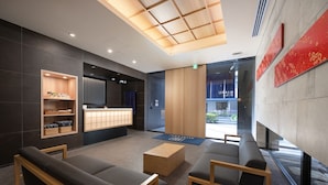 A modern reception area with a wooden reception desk, seating area with sofas and a coffee table, and a large window providing a view of the outside. - MIMARU Tokyo Ueno Inaricho (Tokyo)