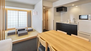 A modern kitchen with a microwave, sink, and cabinets. There is a dining area with a wooden table and chairs. - MIMARU Tokyo Ueno Inaricho (Tokyo)