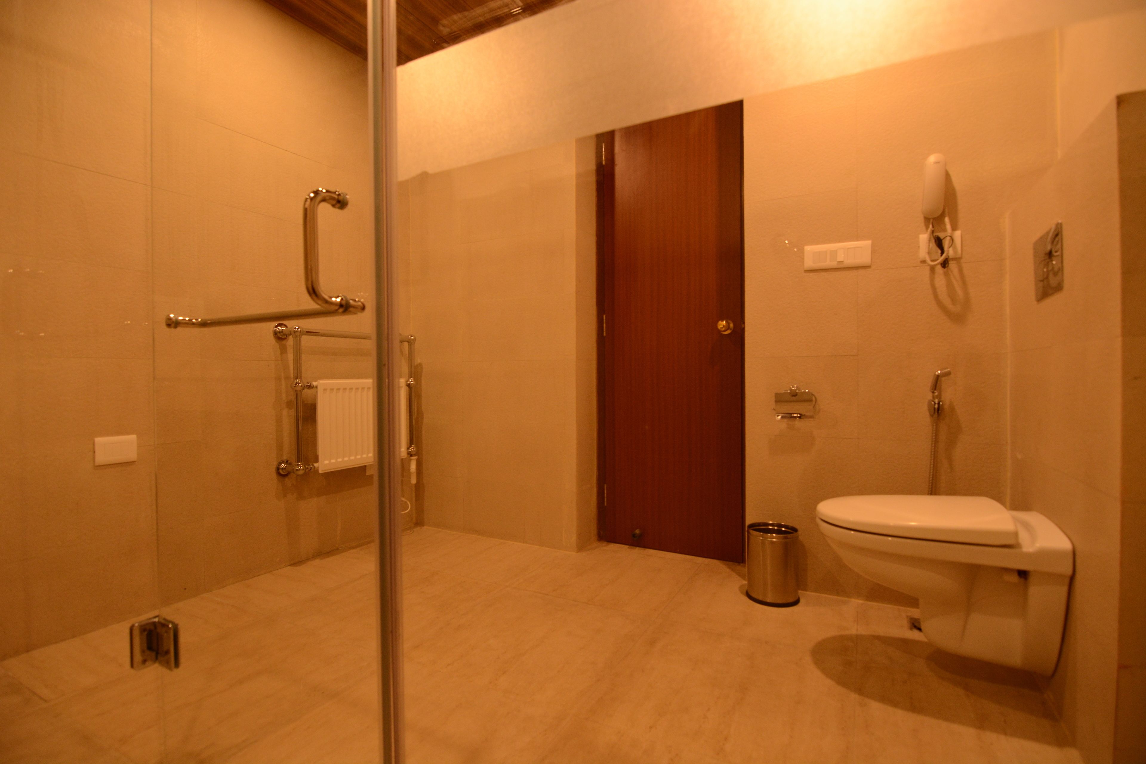 Une salle de bain avec une douche à parois de verre, des toilettes et une porte en bois.
