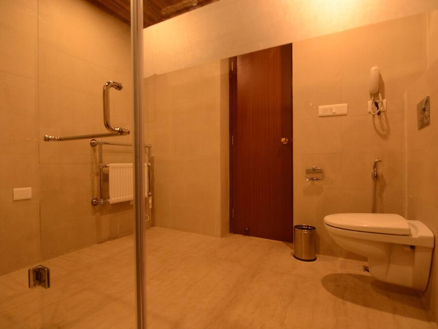 Une salle de bain avec une douche à parois de verre, des toilettes et une porte en bois.