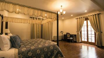 A bedroom with a four-poster bed, a desk, and a chair.