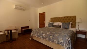 Un dormitorio con una cama grande, una silla, una mesita y una mesilla de noche.
