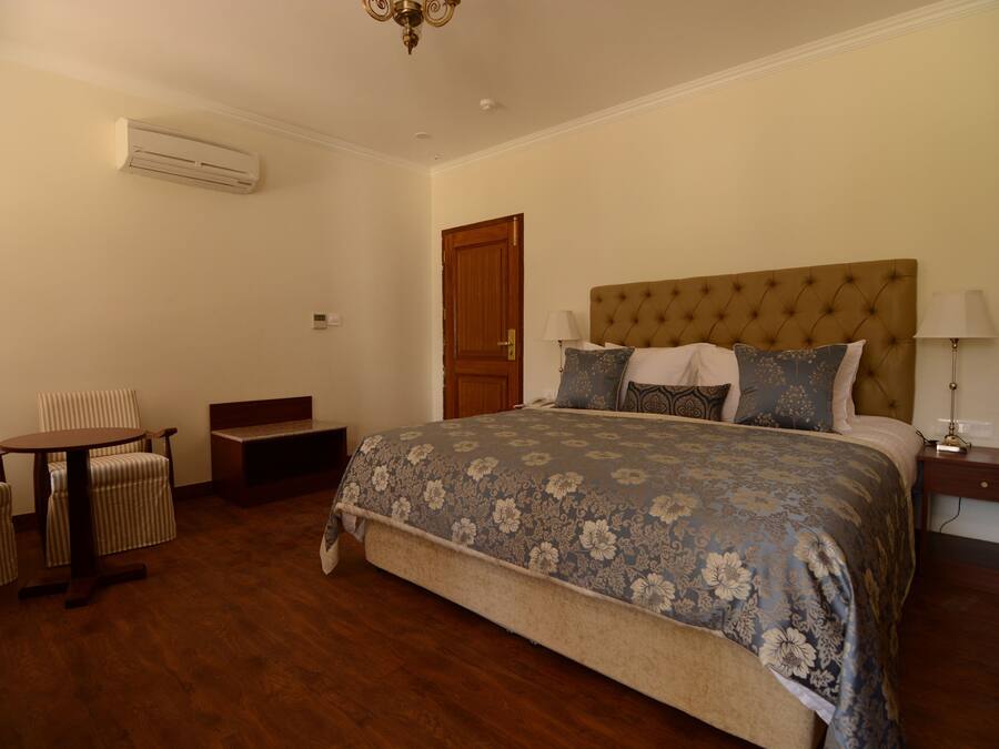 Un dormitorio con una cama grande, una silla, una mesita y una mesilla de noche.
