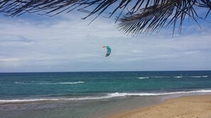A beach with clear blue water and a person flying a kite. - VillaNicky Rincon, PR 2,800 Sqft Beach Front Oasis  (Rincon)
