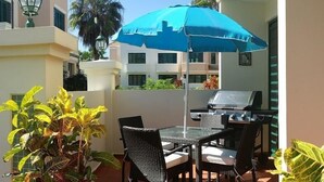 An outdoor patio with a table and chairs, a grill, and potted plants. - VillaNicky Rincon, PR 2,800 Sqft Beach Front Oasis  (Rincon)