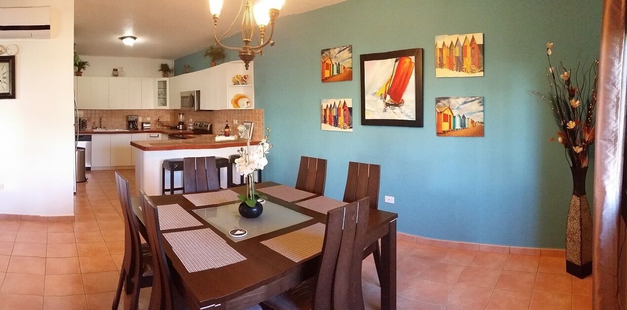 A dining area with a wooden table and chairs, a vase with flowers, and artwork on the wall.