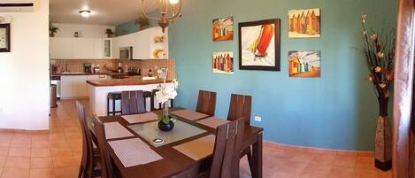 A dining area with a wooden table and chairs, a vase with flowers, and artwork on the wall.