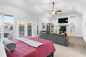 Ein geräumiges Schlafzimmer mit einem großen Bett, einem grauen Sofa und einem Fernseher im Wohnbereich.