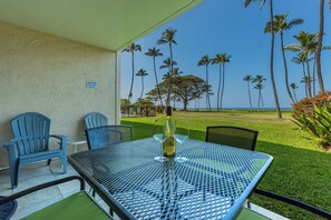 A patio with a table, chairs, and a bottle of wine.