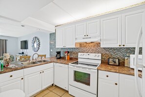 Une cuisine avec des meubles blancs, une cuisinière et un lave-vaisselle.