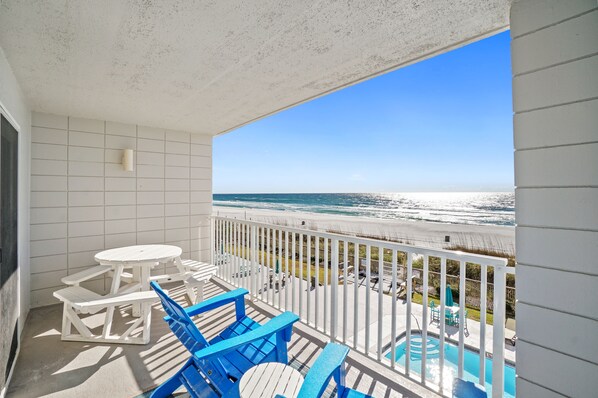 Un balcon avec piscine, des murs recouverts de carreaux blancs et une vue sur la plage.