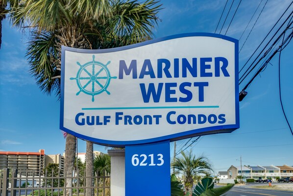 A sign for Mariner West Gulf Front Condos with a compass symbol and the address 6213.