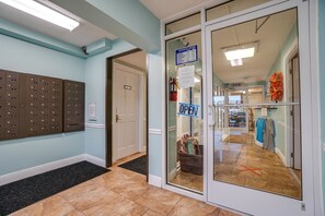 A hotel lobby with a reception desk, mailboxes, and a clear glass door leading to the business hours sign.