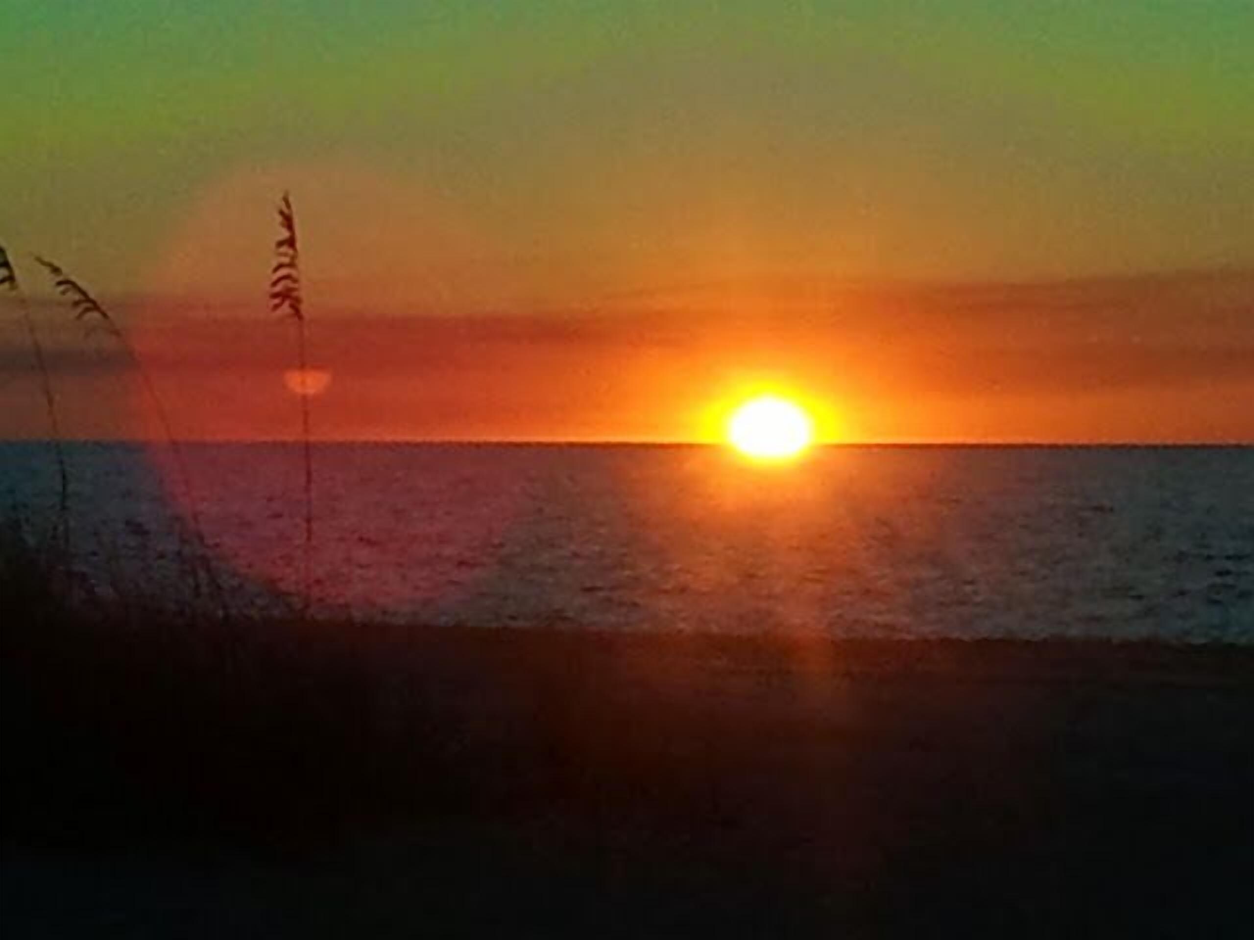 A sunset over a body of water with a clear horizon.